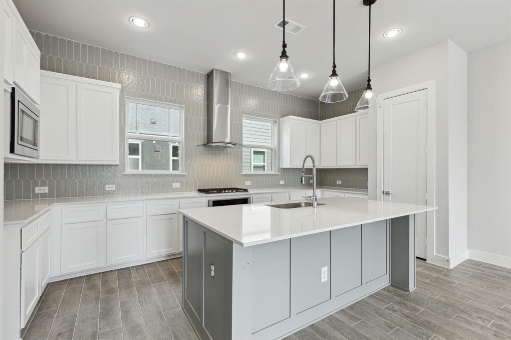 a kitchen with a sink stove cabinets and wooden floor