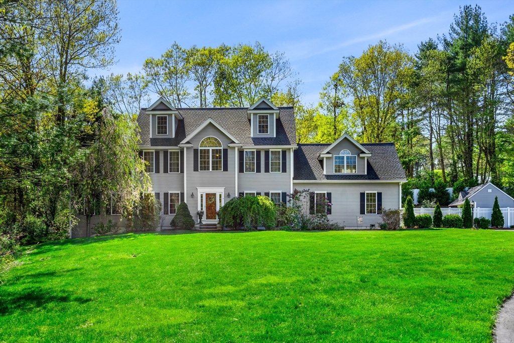 a front view of a house with a garden and trees