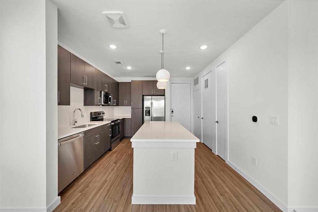 a kitchen with stainless steel appliances kitchen island granite countertop a sink and a refrigerator