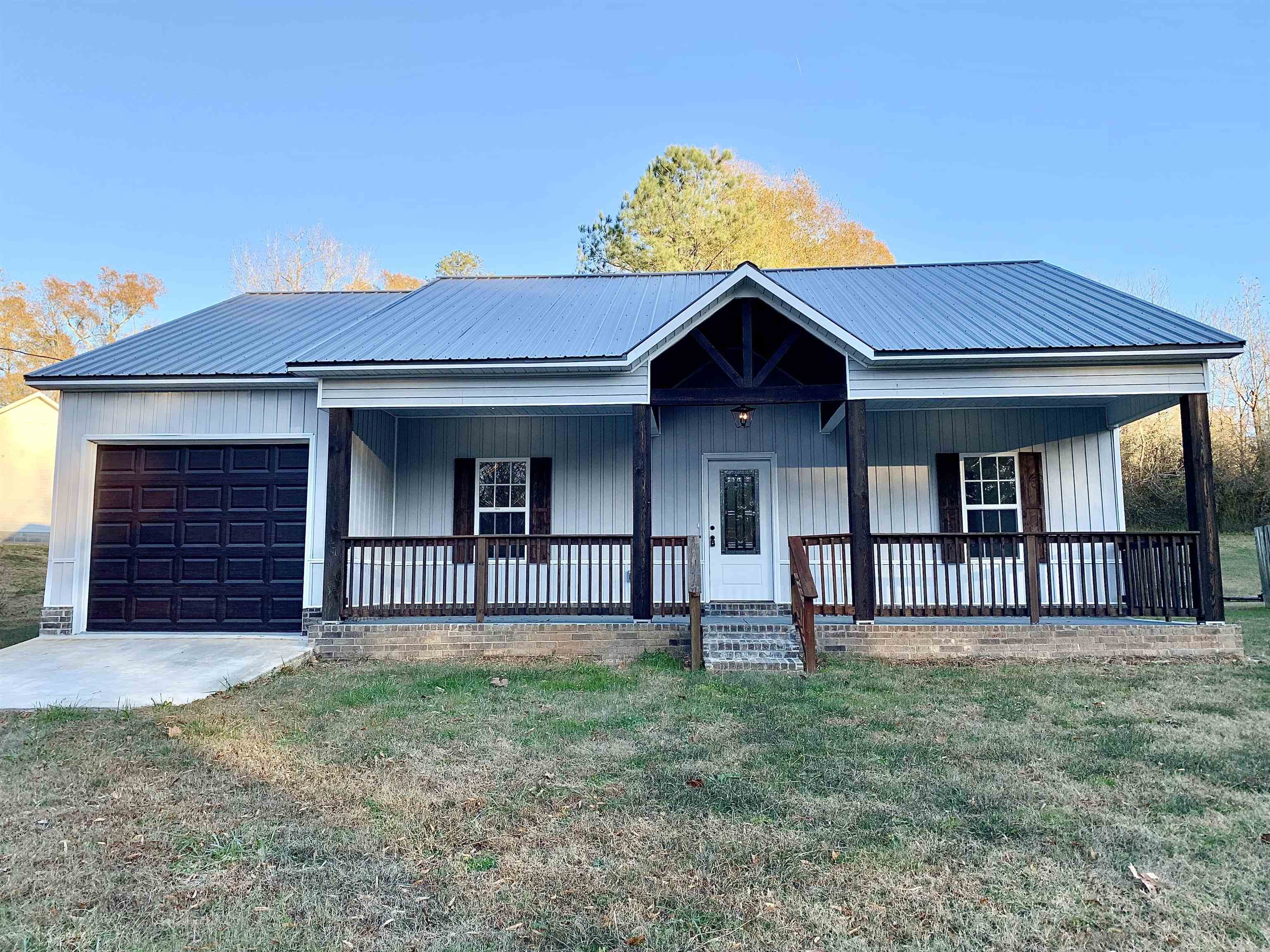 View of front of home featuring covered porch, a garage, and a front lawn