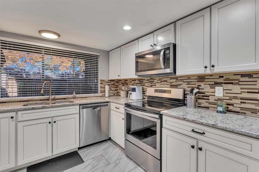 a kitchen with granite countertop white cabinets stainless steel appliances and a sink