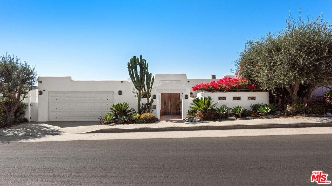 a front view of a house with a yard and potted plants