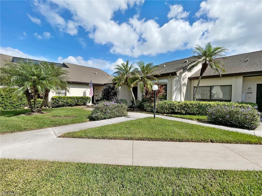 a palm tree sitting in front of a house with a yard