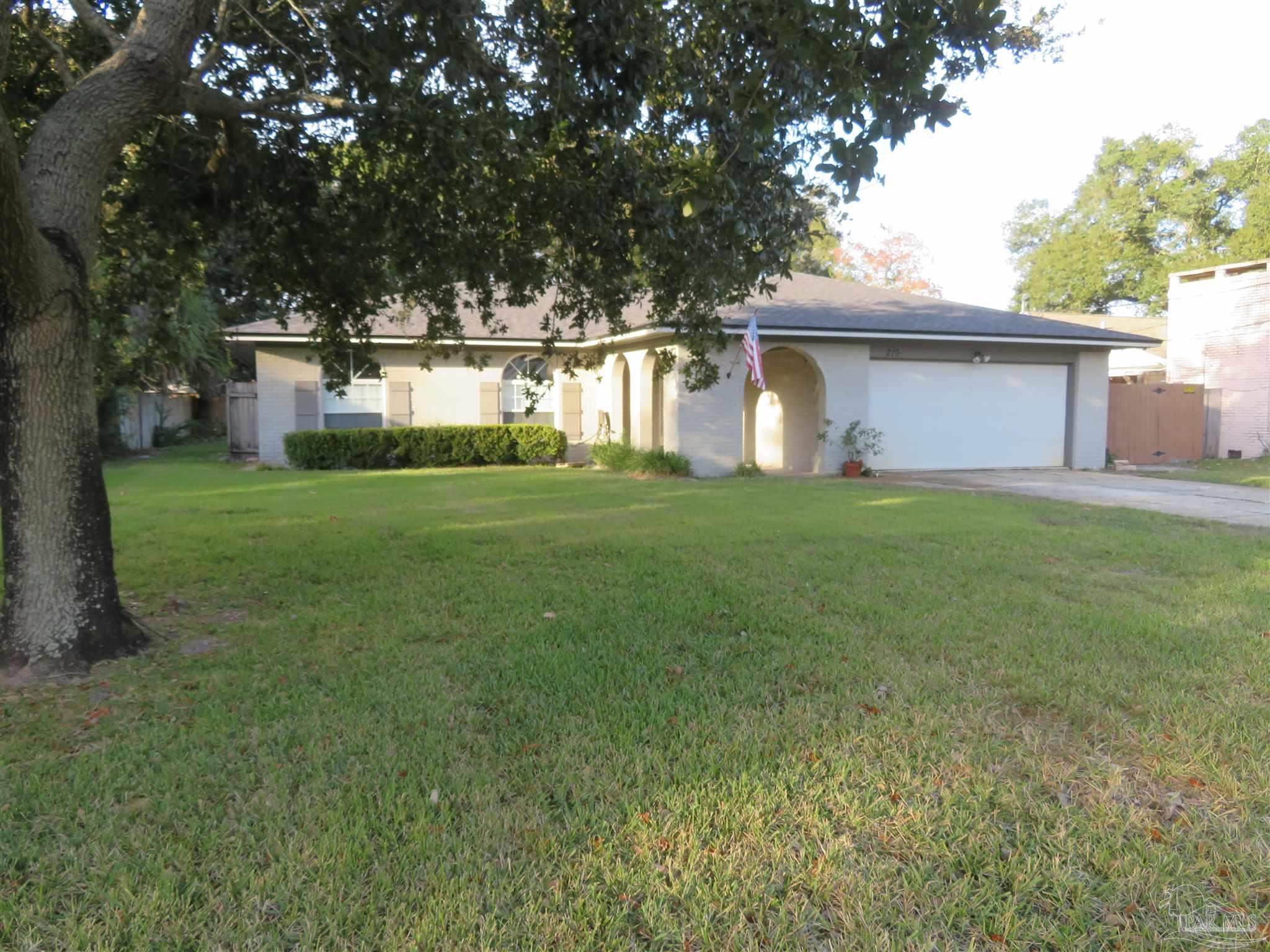 a view of a house with a yard and large trees