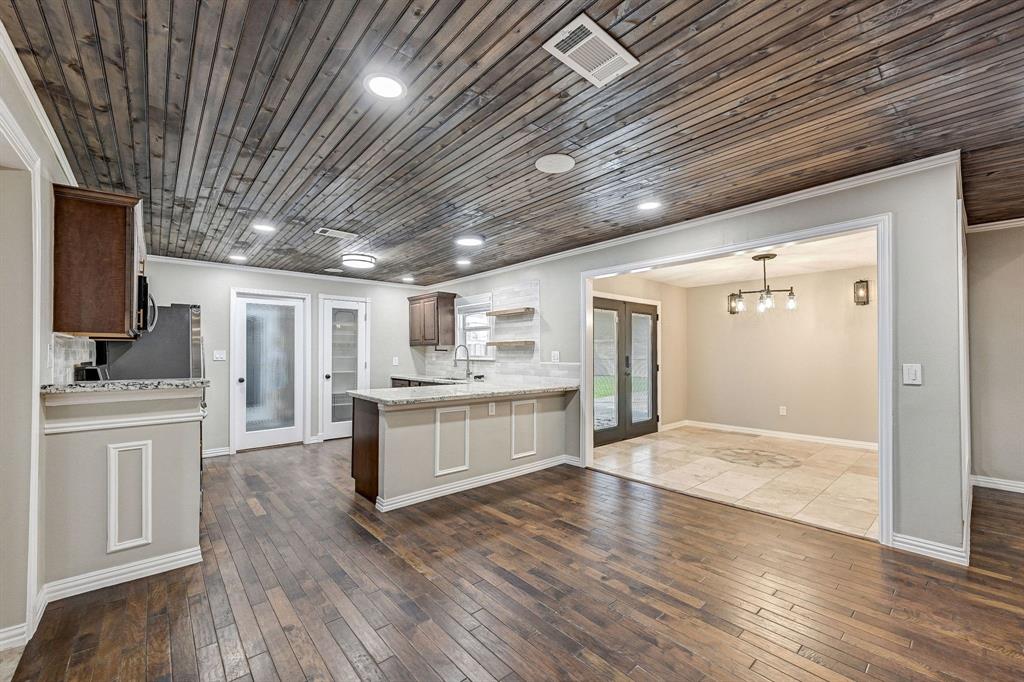 a large kitchen with kitchen island wooden floors granite counter tops and white stainless steel appliances