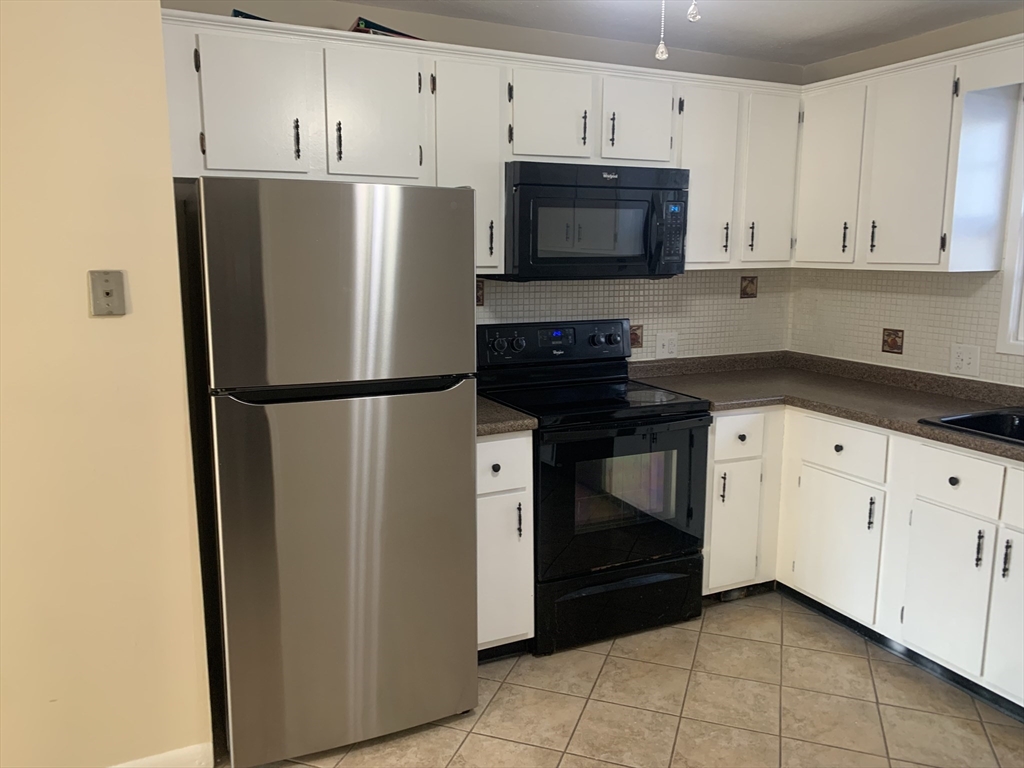 a kitchen with a refrigerator stove and white cabinets