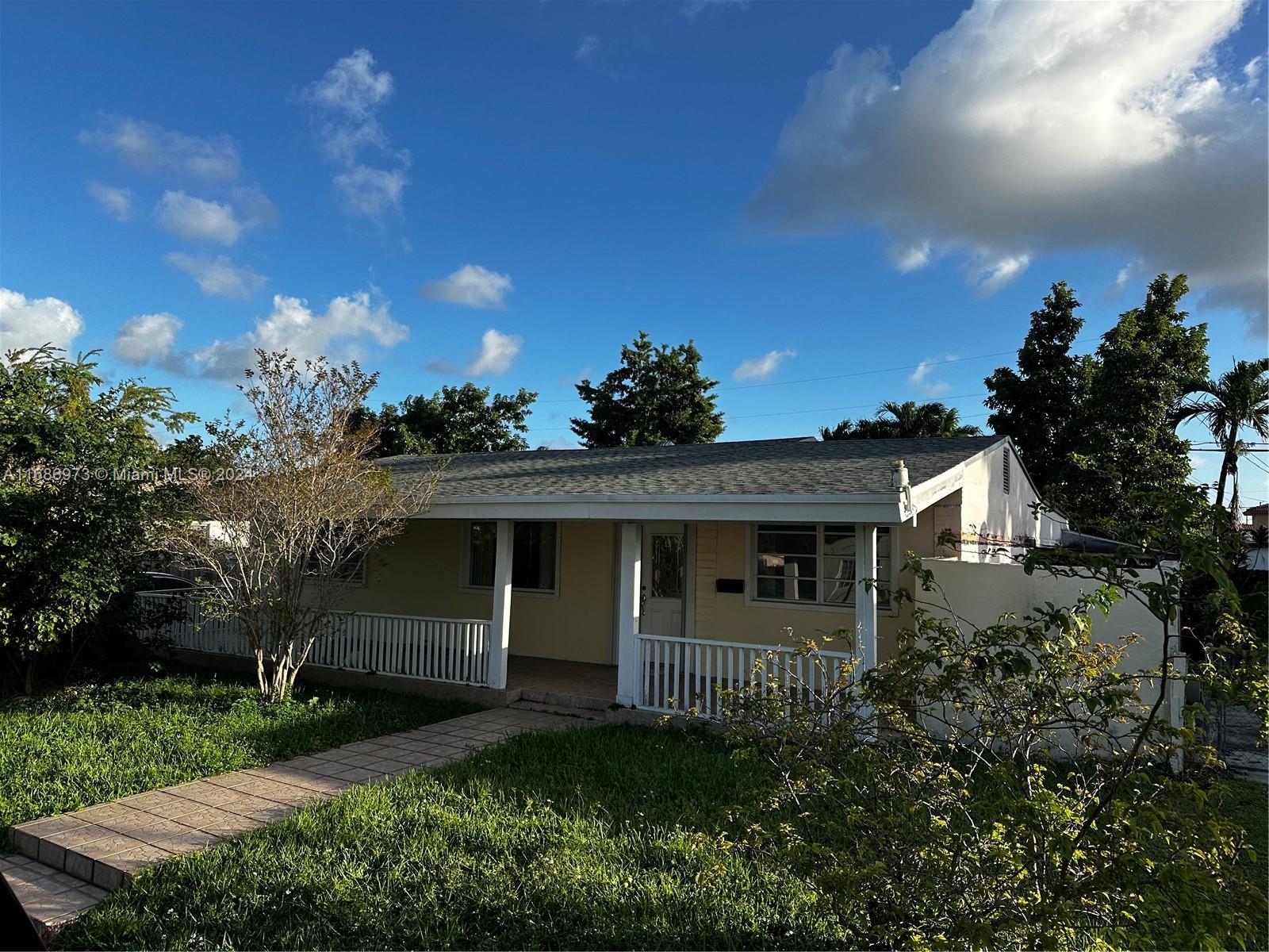 a view of a house with a small yard and a large tree