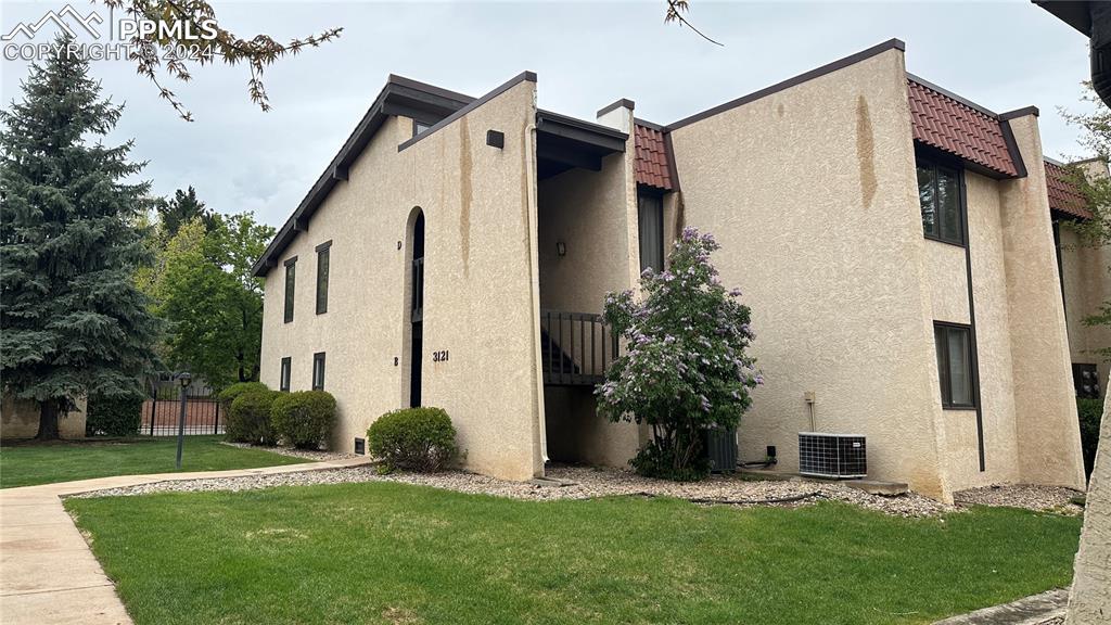 View of property exterior featuring central AC unit and a lawn