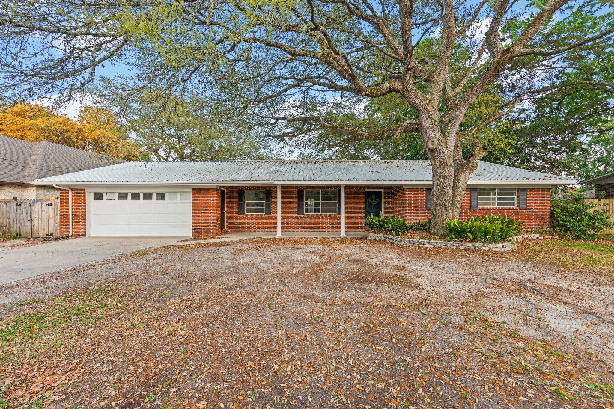 a view of a house with a yard and large tree