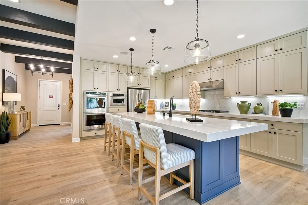 a kitchen with stainless steel appliances kitchen island granite countertop a table chairs sink and cabinets