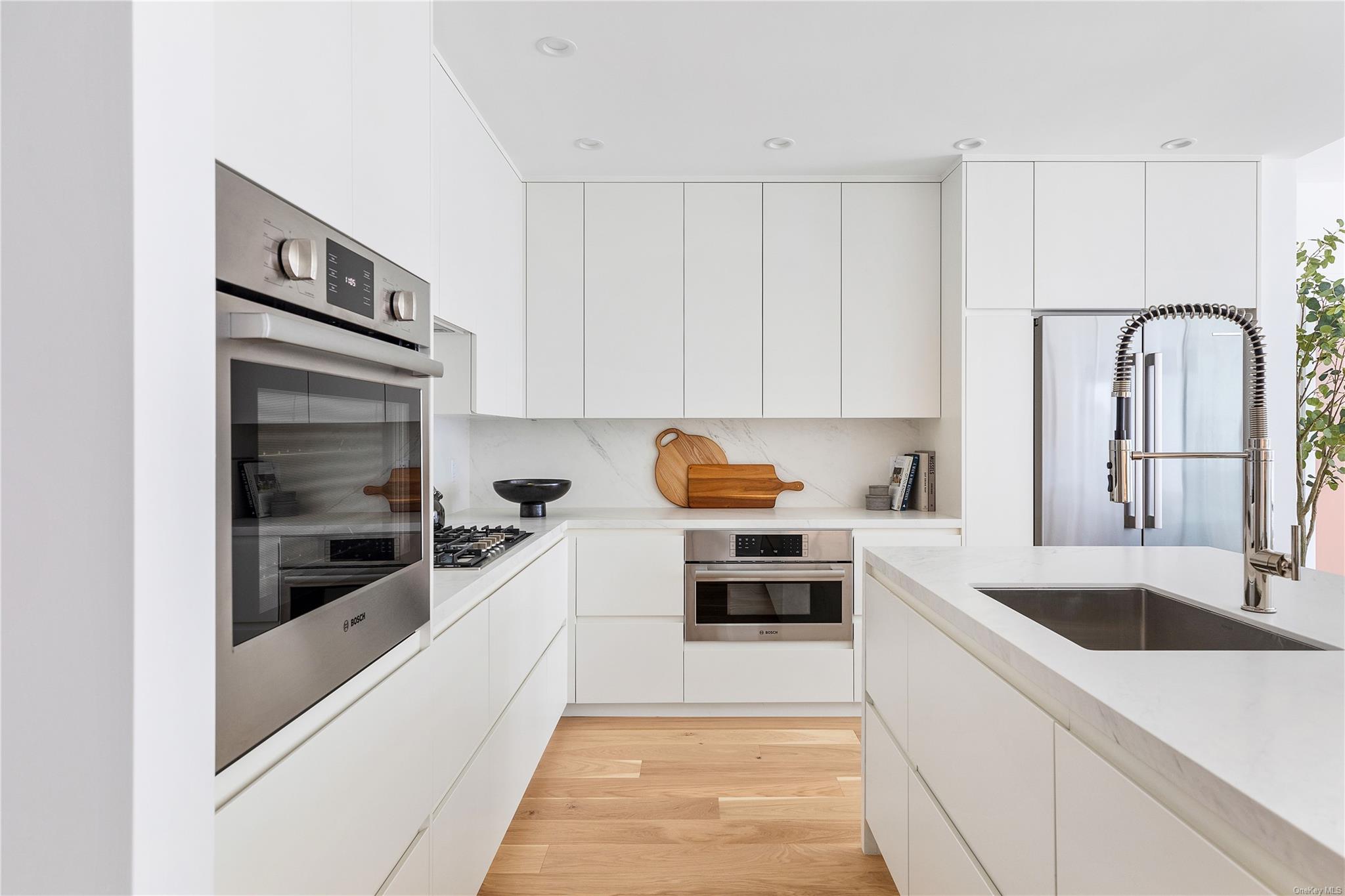 Kitchen featuring stainless steel appliances, light countertops, a sink, and modern cabinets