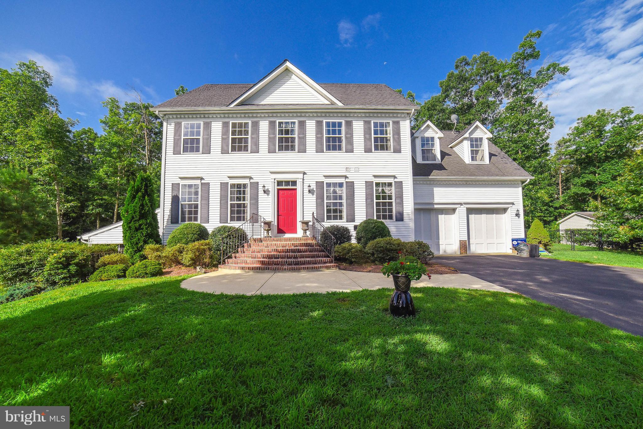 a front view of a house with garden and trees