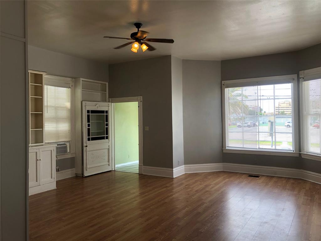 an empty room with wooden floor closet and windows