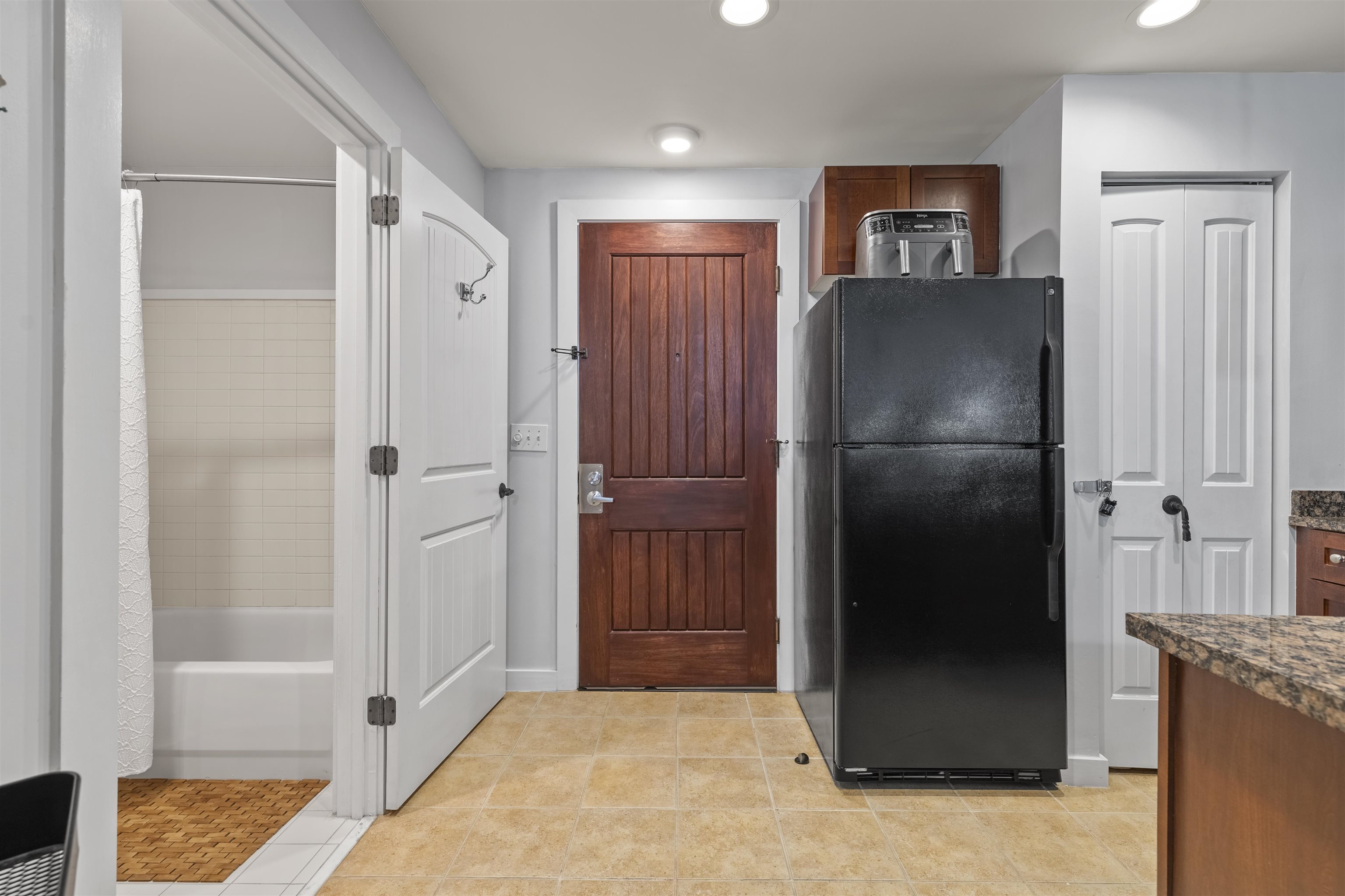 a view of a refrigerator in kitchen and an empty room