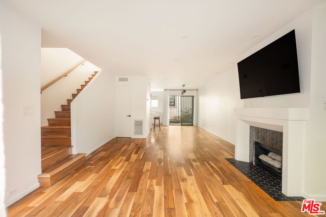 a view of a livingroom with wooden floor and a fireplace