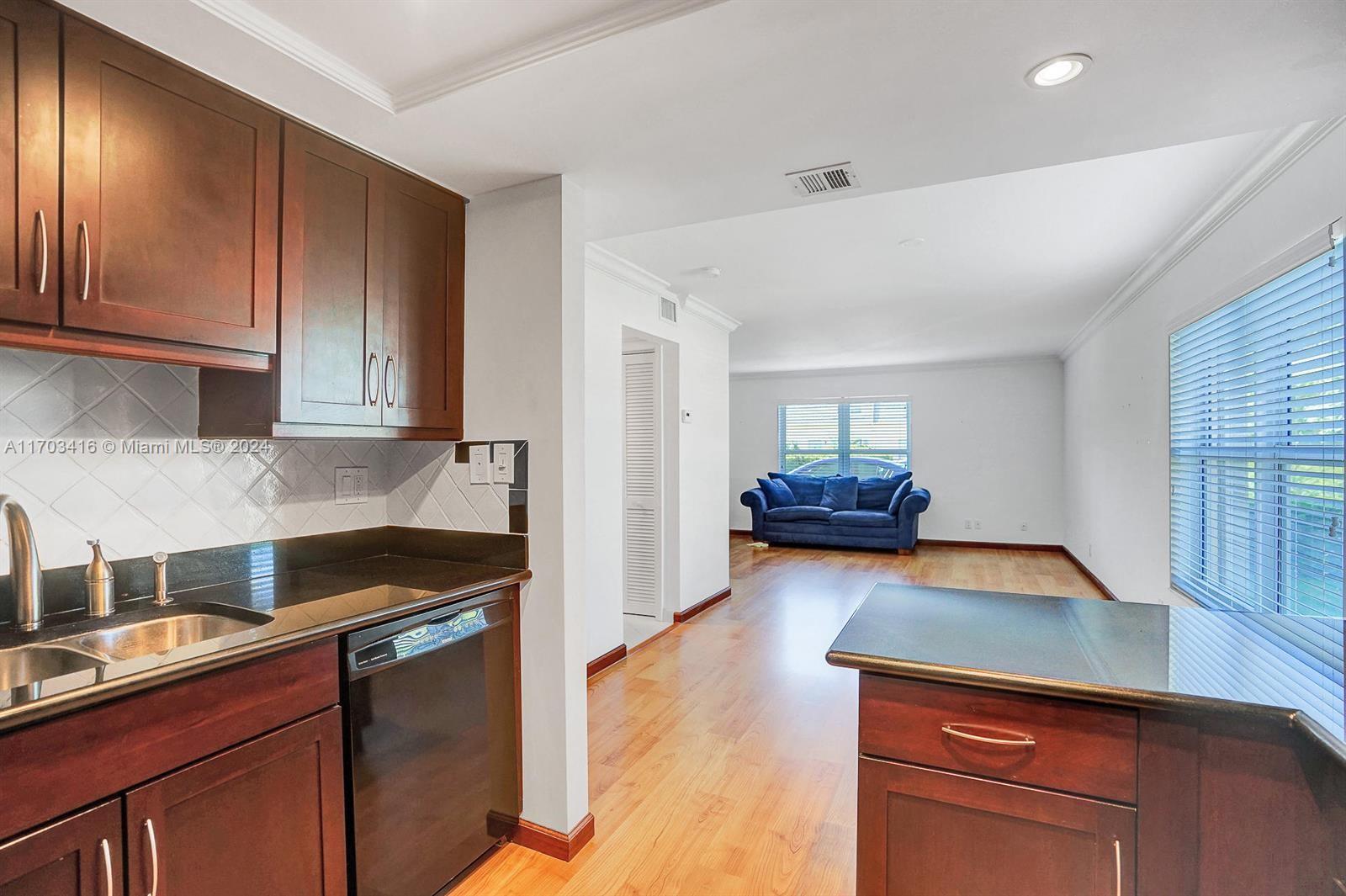 a kitchen with granite countertop a sink cabinets and wooden floor