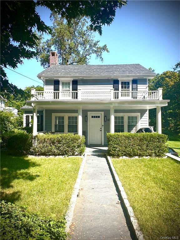 View of front facade with a balcony and a front lawn