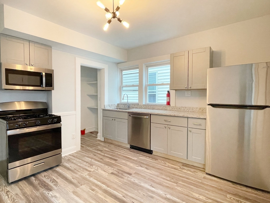 a kitchen with granite countertop a refrigerator stove top oven and sink