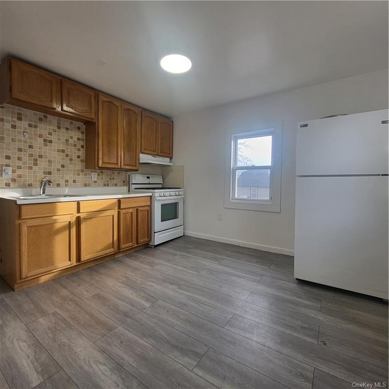 a kitchen with stainless steel appliances granite countertop a sink cabinets and wooden floor