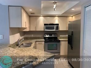 a kitchen with kitchen island granite countertop a stove and a sink