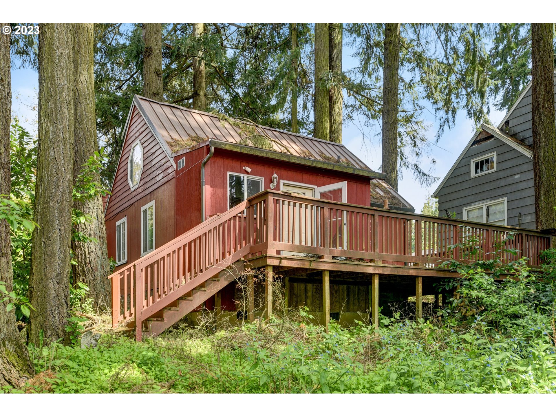 a backyard of a house with a deck and large trees