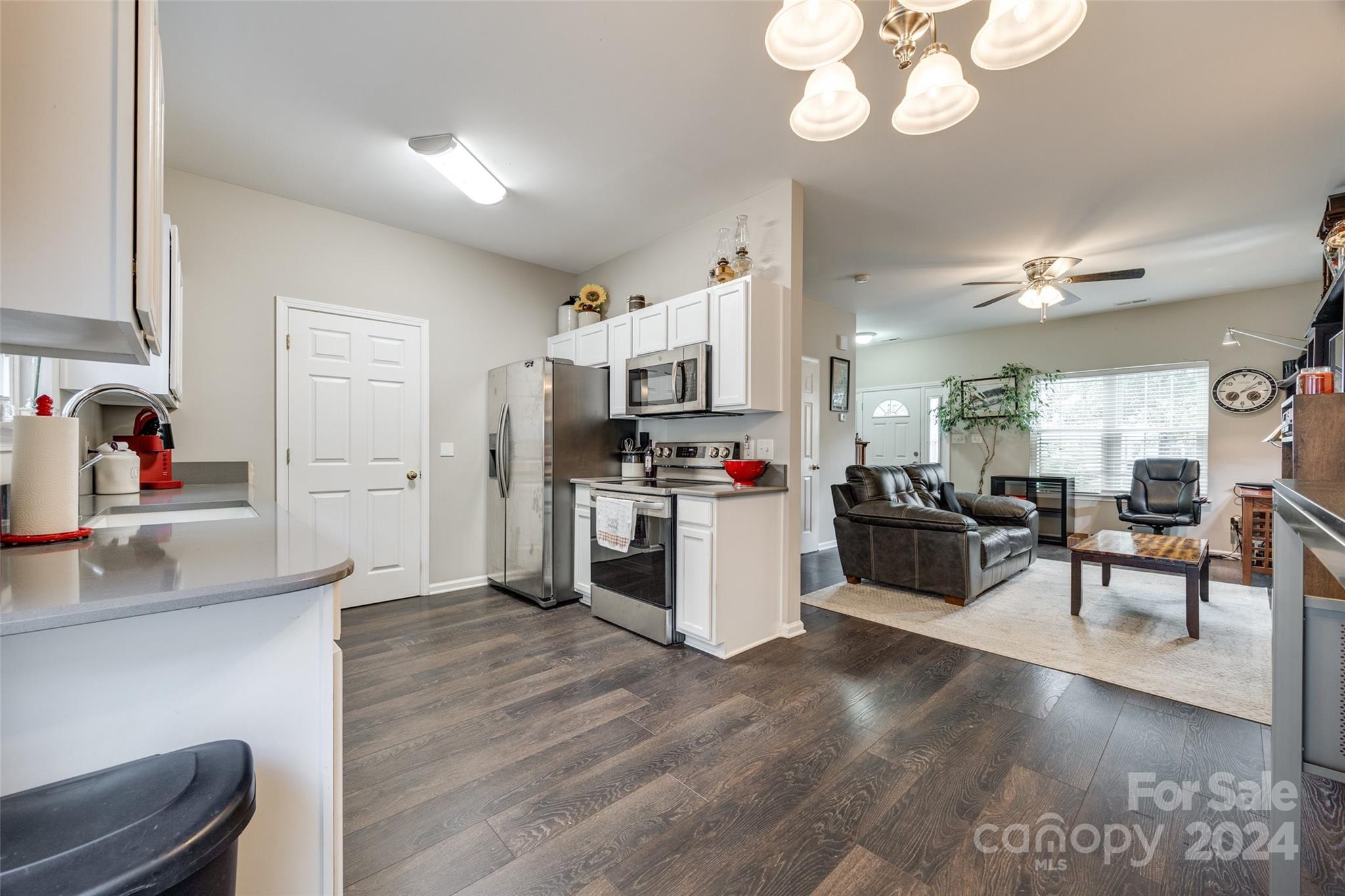 a kitchen with stainless steel appliances kitchen island granite countertop a refrigerator a sink dishwasher a dining table and chairs with wooden floor