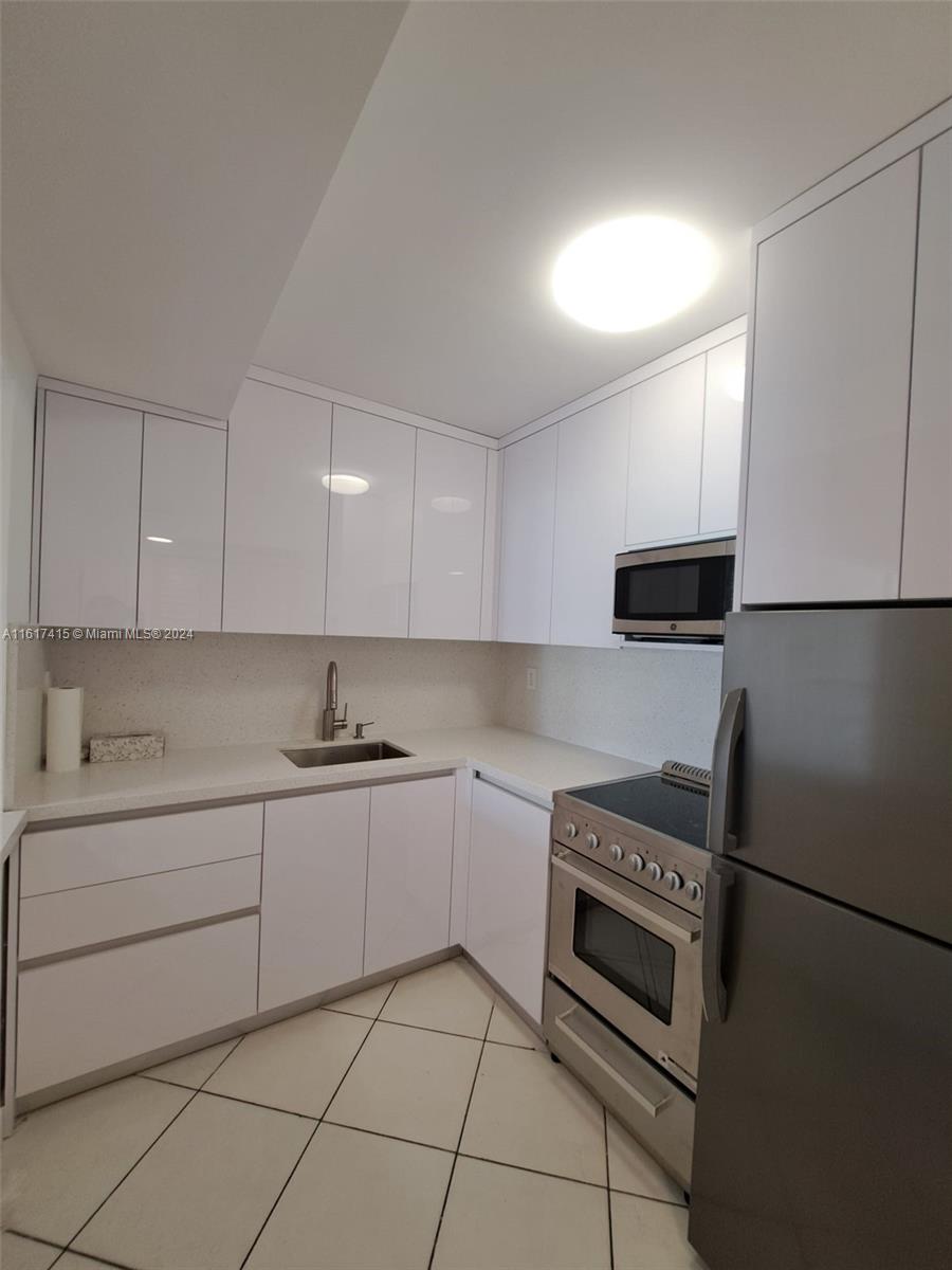 a kitchen with stainless steel appliances granite countertop a sink and a refrigerator