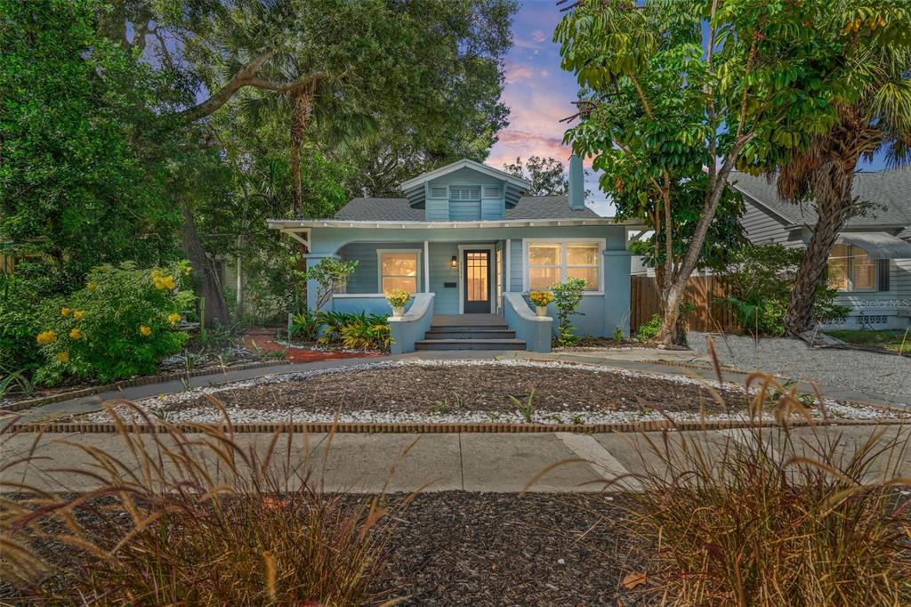 a front view of a house with a yard and potted plants