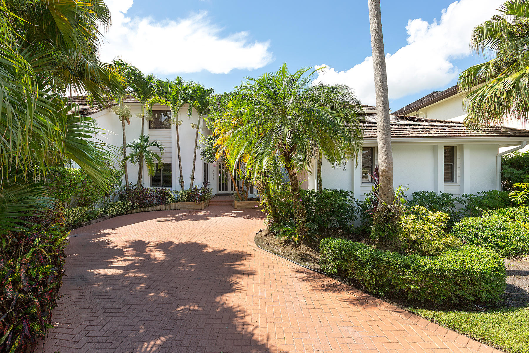 a view of a house with a yard and palm trees