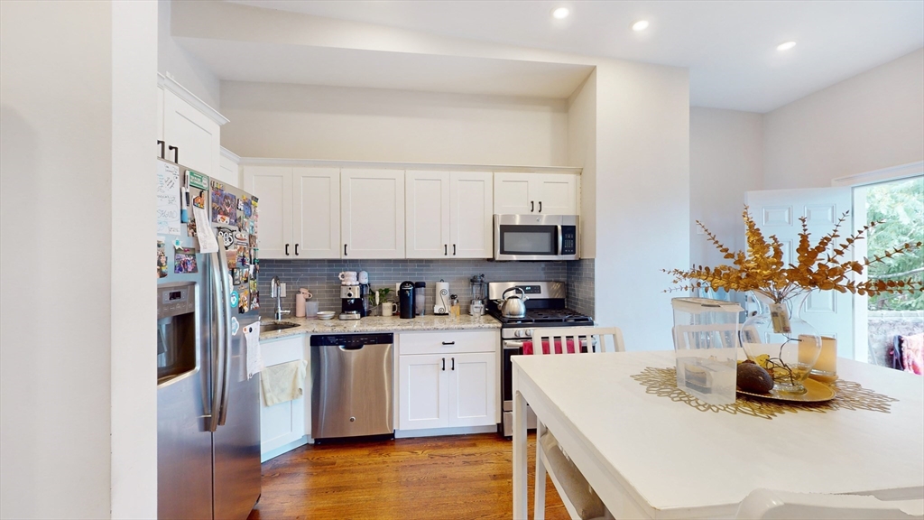 a kitchen with stainless steel appliances kitchen island granite countertop a sink dishwasher stove and white cabinets