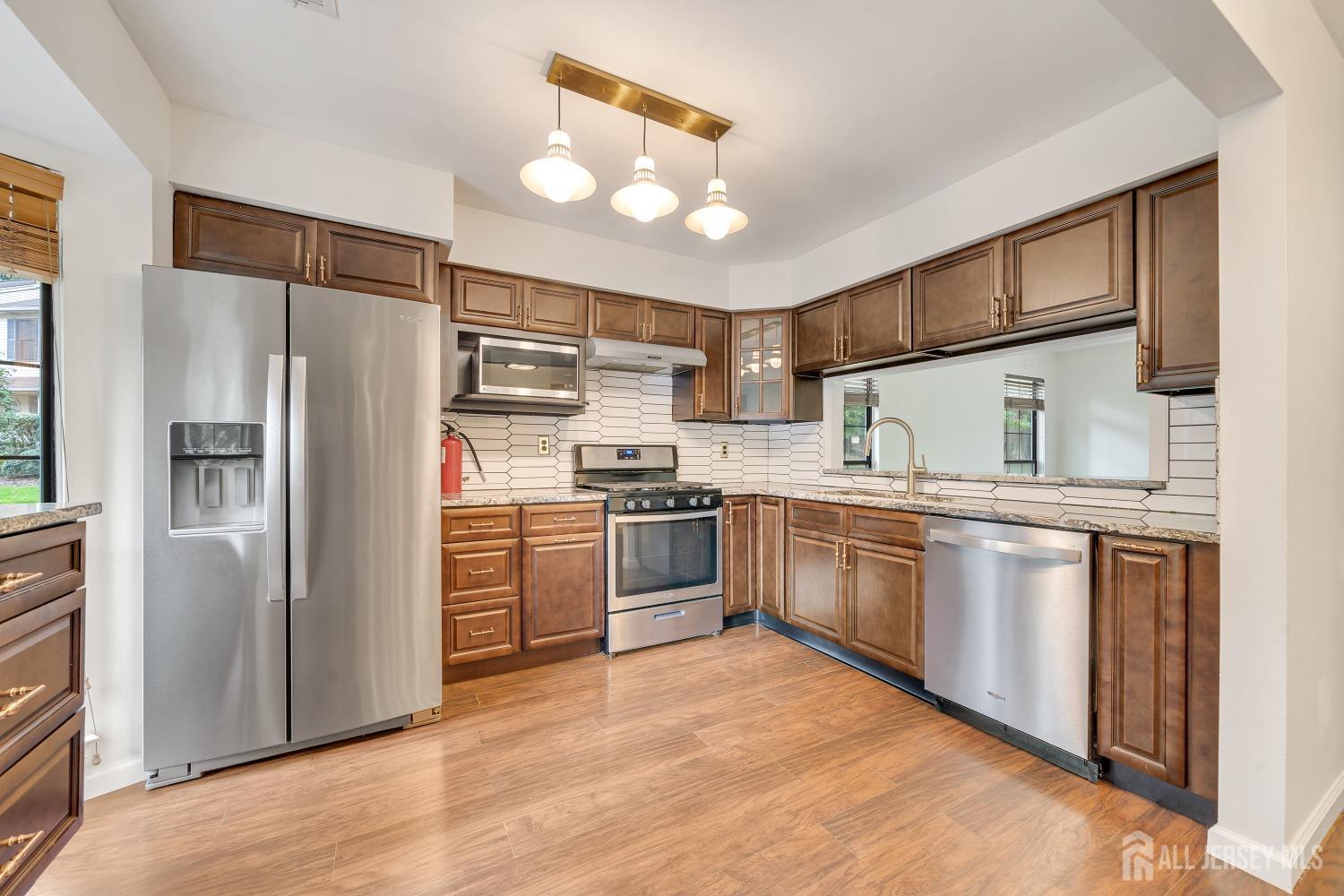 a kitchen with stainless steel appliances granite countertop a refrigerator and a stove top oven