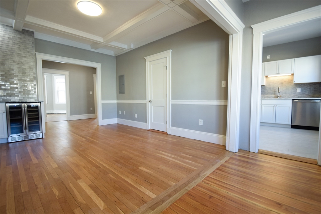 a view of a room with wooden floor and a kitchen