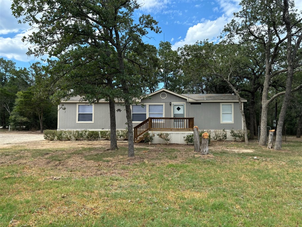 a front view of house with yard and trees in the background