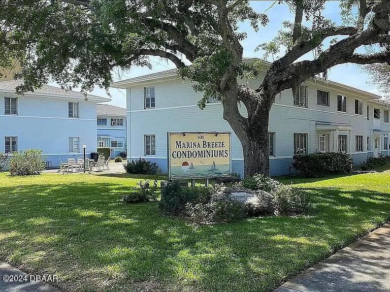 a sign board with a house in the background