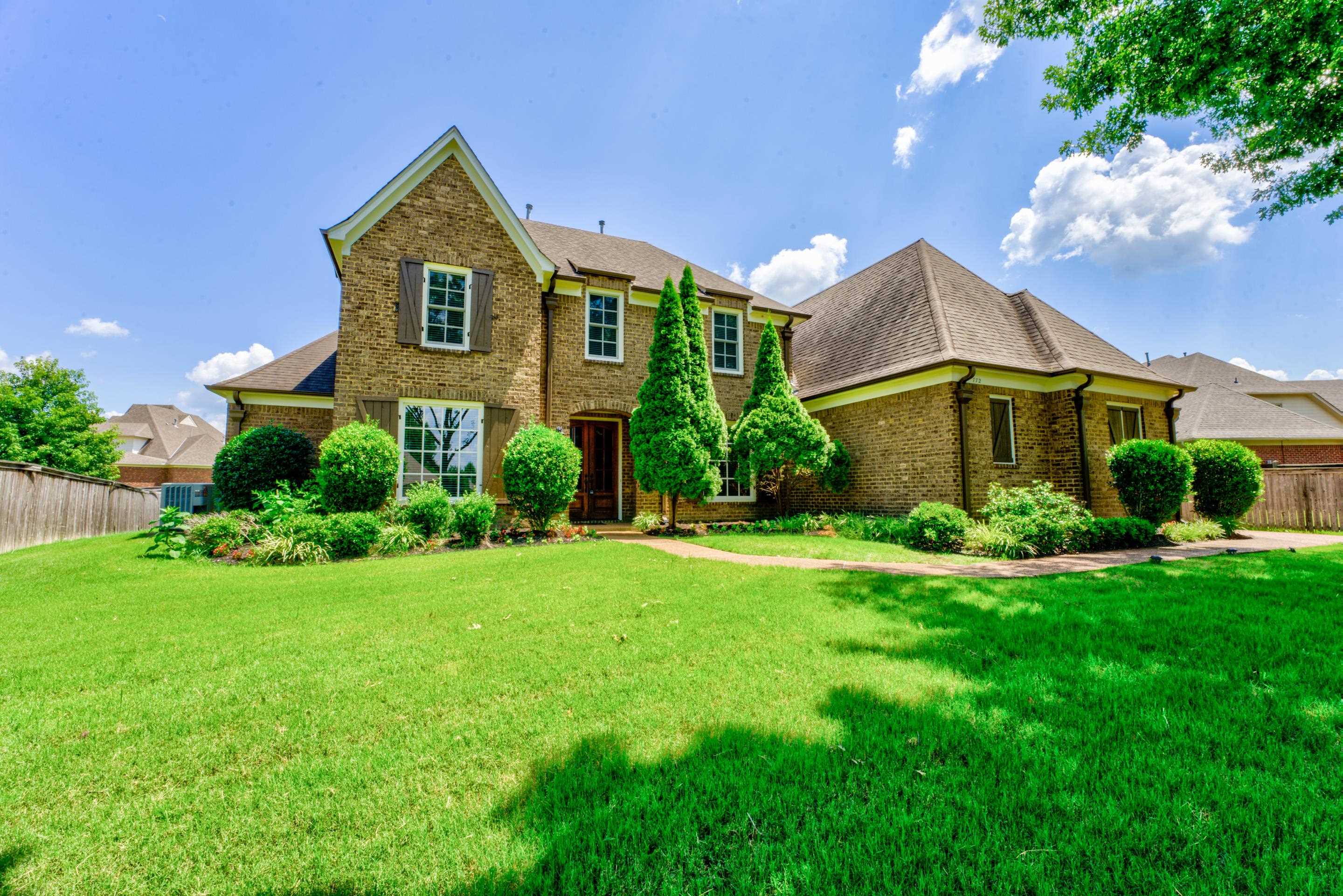 a front view of a house with a yard and potted plants