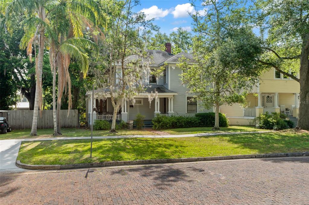 a view of a house with a big yard and palm trees