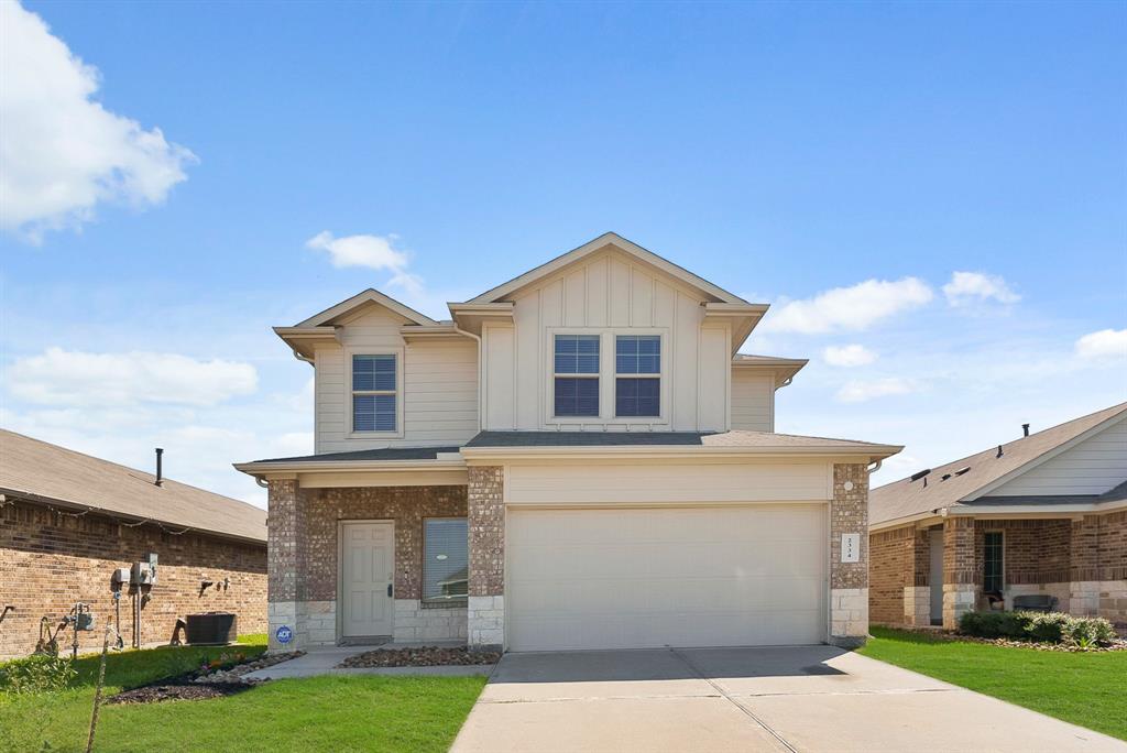 This is a two-story, contemporary suburban home featuring a mix of stone and siding facade, a two-car garage, and a nice size front lawn.