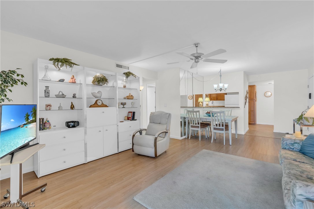 a living room with furniture and kitchen view with wooden floor