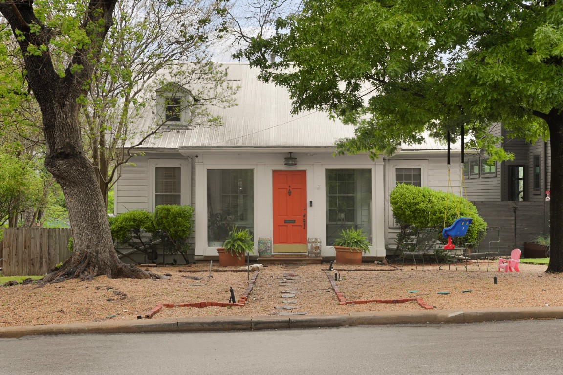 front view of house with potted plants and a large tree