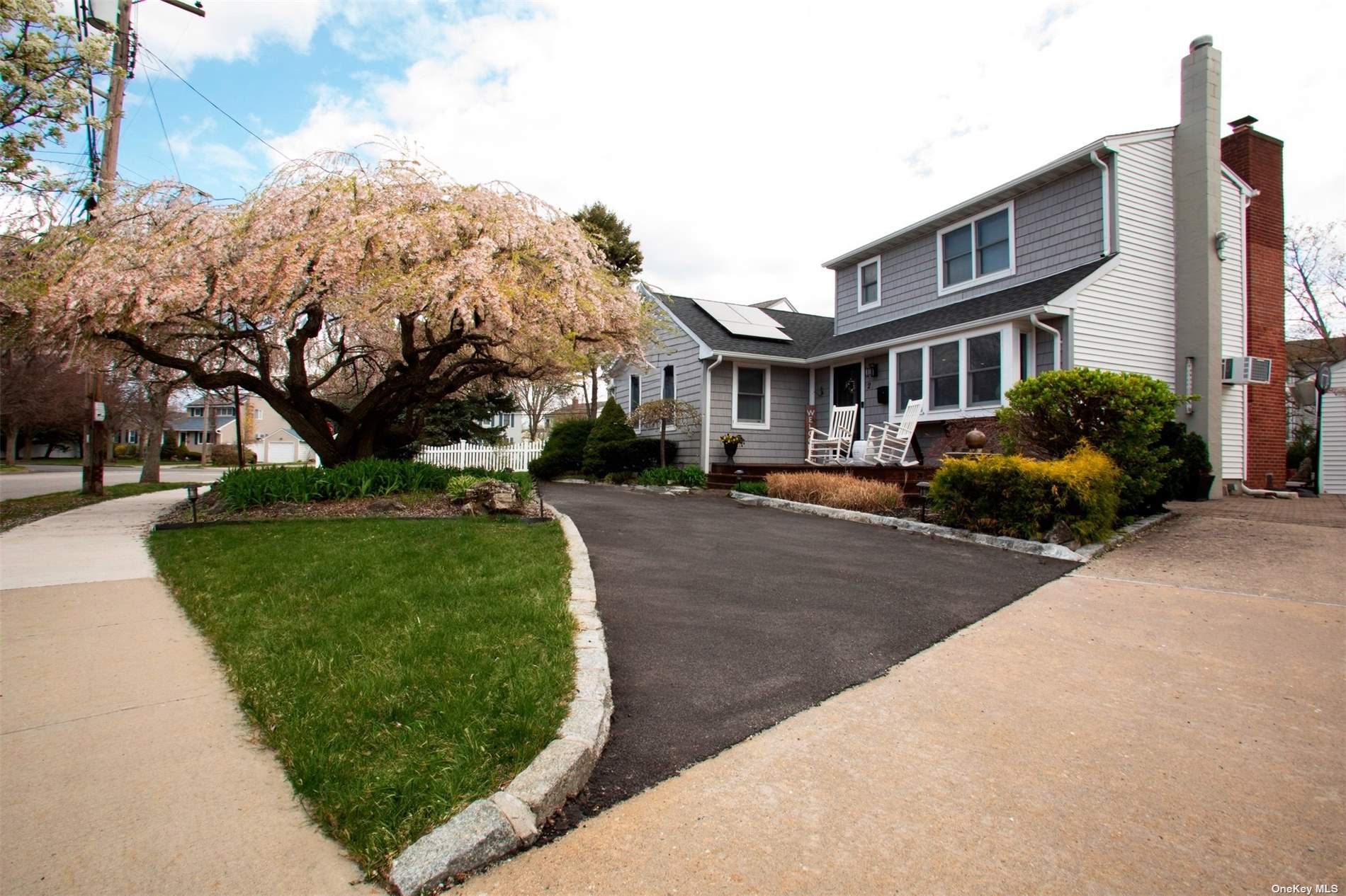 a front view of a building with a garden and trees