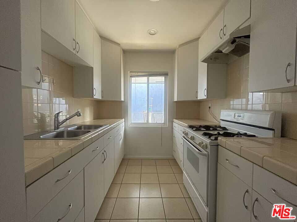 a kitchen with stainless steel appliances granite countertop a sink stove and cabinets