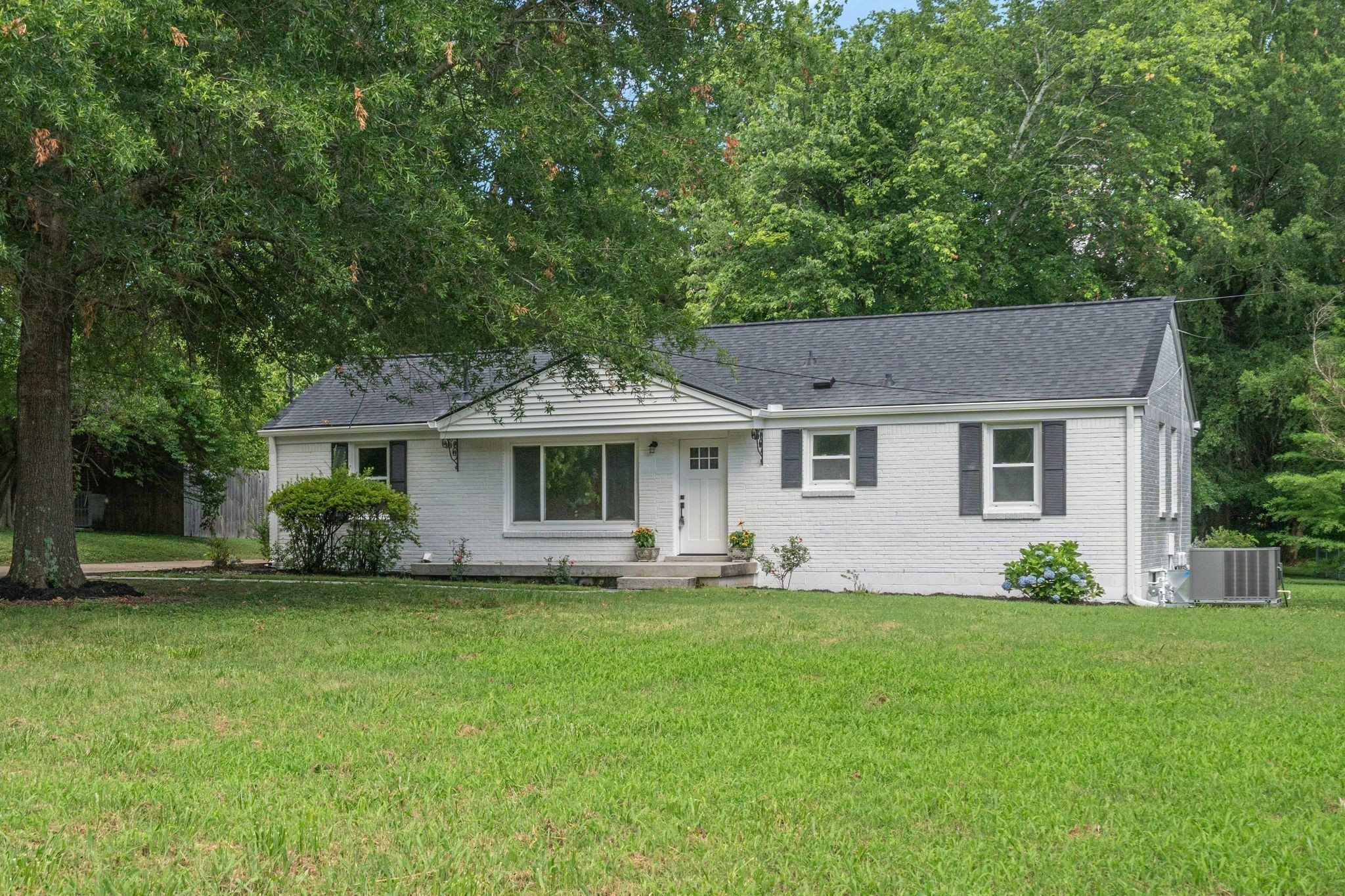 a front view of a house with a garden and trees