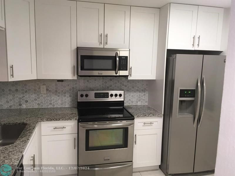 a kitchen with stainless steel appliances white cabinets and a refrigerator