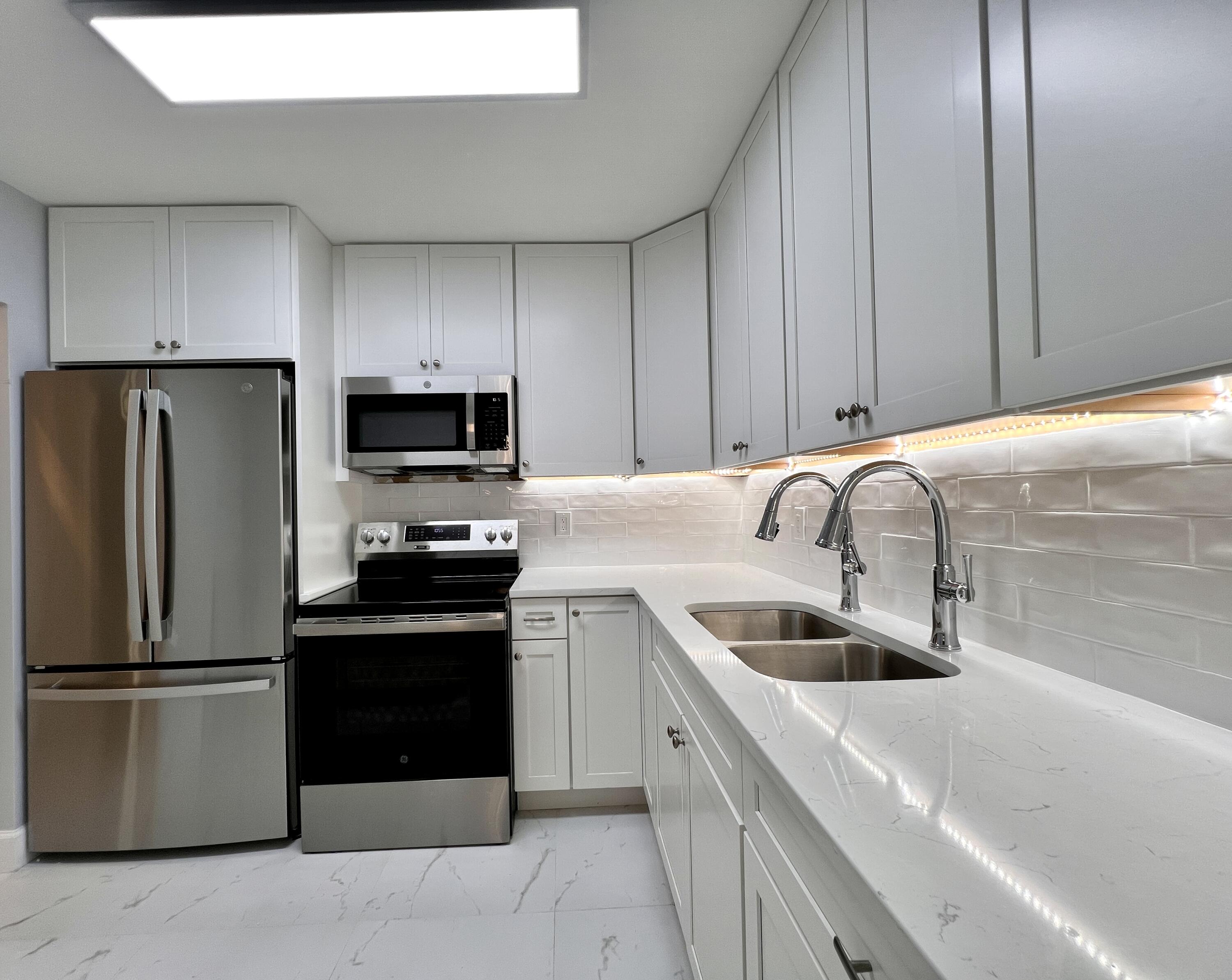 a kitchen with a sink a microwave a refrigerator and cabinets