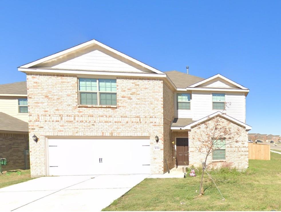 View of front facade featuring a garage and a front lawn