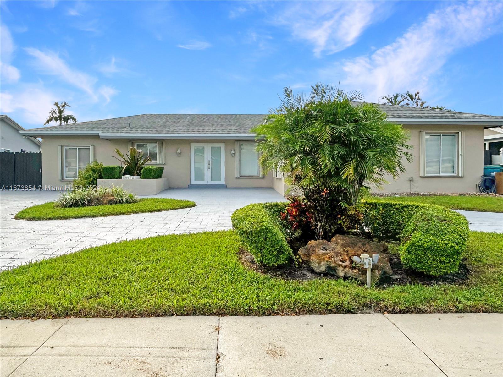 a front view of a house with a yard and potted plants