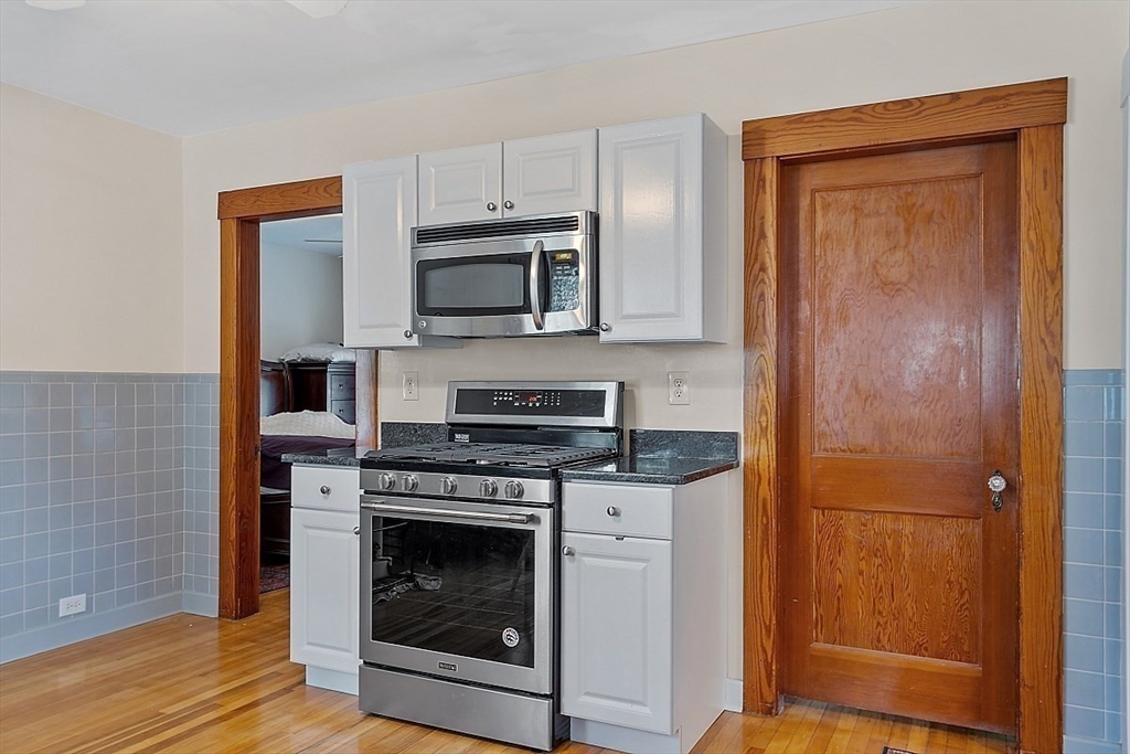 a kitchen with cabinets stainless steel appliances and wooden floor