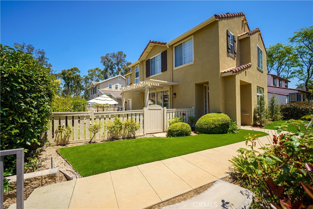 a view of a white house with a big yard and potted plants