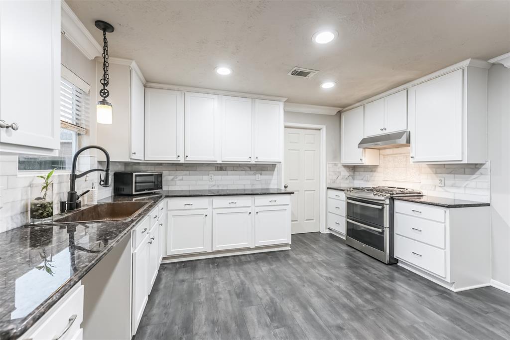 a kitchen with granite countertop a sink stainless steel appliances and cabinets