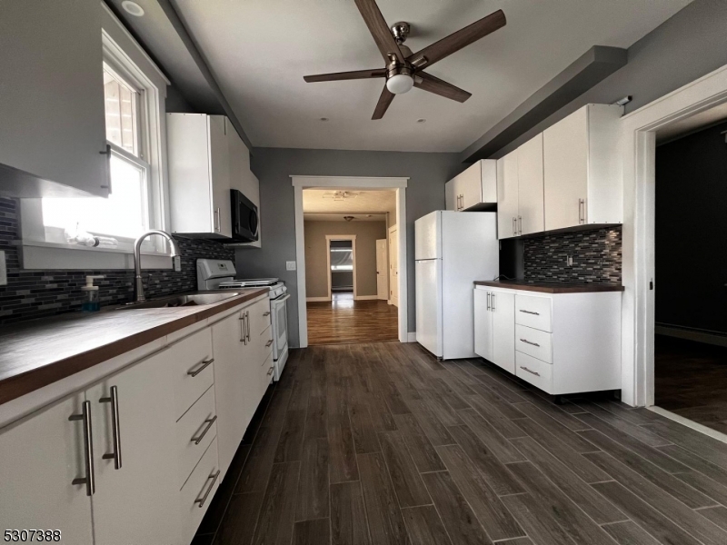 a large white kitchen with wooden floor and a sink